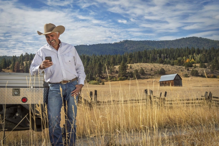 Commercial Advertising Photography. Rancher checks his cell phone.